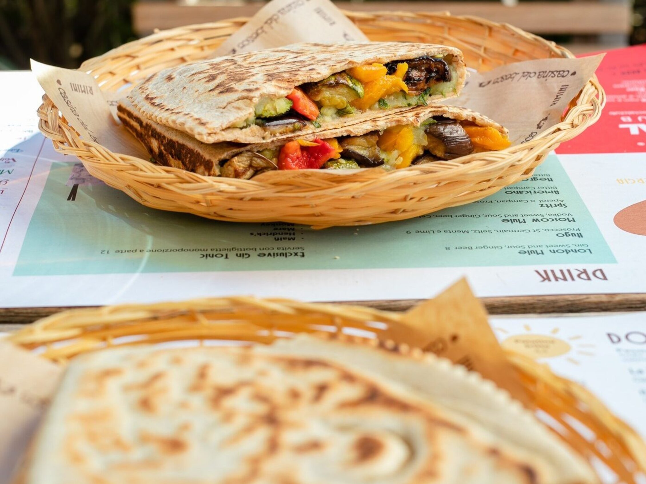 a table with two wicker plates with delicious stuffed piadinas 