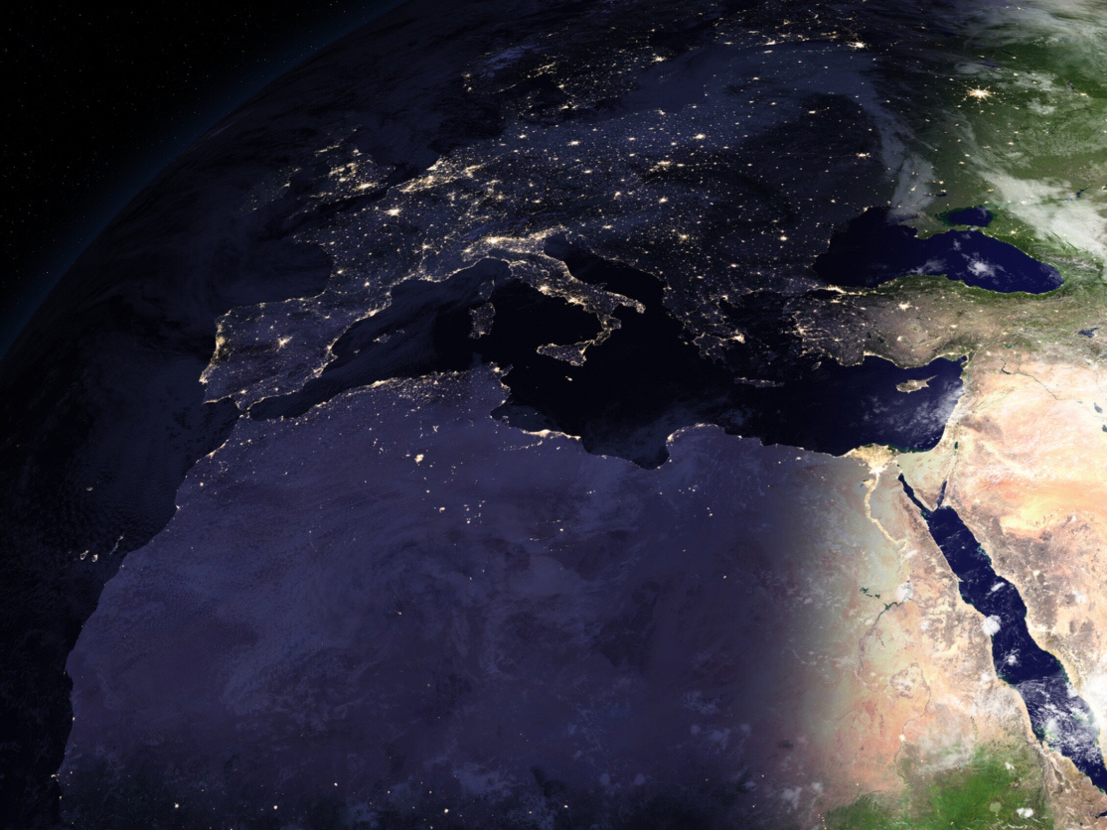 Satellite view of Italy at night from space, showing the glowing city lights and the Mediterranean coastline.