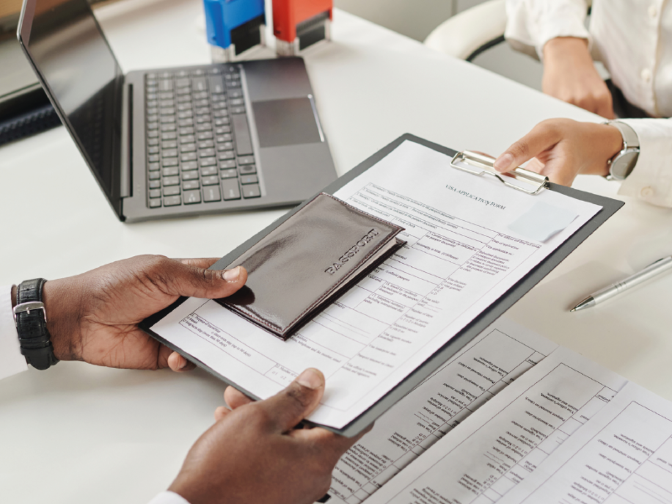Visa application documents being reviewed at an office desk, supporting international travel arrangements for attending BEX – Beyond Exploration expo