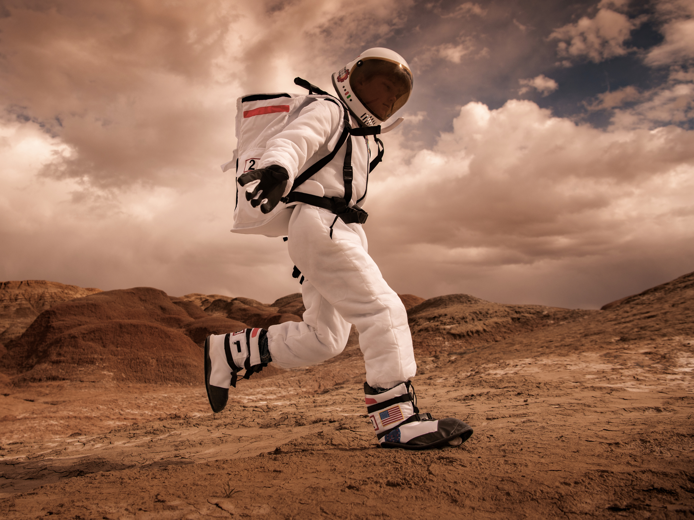 Side view of an astronaut in a full space suit running through outer space